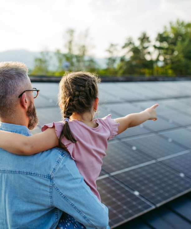 Rear,View,Of,Dad,With,Girl,On,Roof,With,Solar